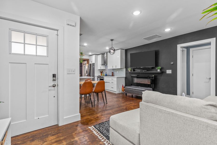 An open living room and kitchen with hardwood floors and a dark accent wall